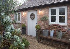 a wooden bench sitting in front of a brick building with potted plants on it