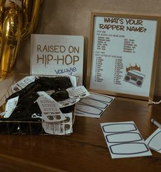 a wooden table topped with lots of papers and cards next to a sign that says raised on hip hop volume 1