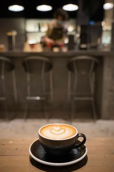 a cappuccino sitting on top of a wooden table in front of a bar