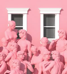 a group of statues in front of a pink building with shutters on the windows