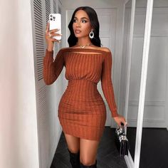 a woman taking a selfie while wearing a brown sweater dress and black cowboy boots