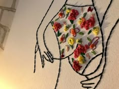 a drawing of a woman with flowers on her stomach and hands behind her back, in front of a white wall