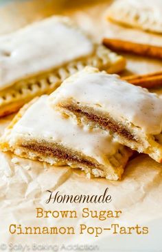 some cookies with icing and cinnamon sticks on top of paper next to each other