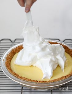 a person is spreading whipped cream on top of a pie