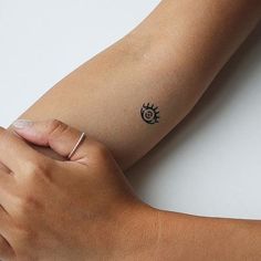 a woman's arm with a small sun tattoo on the left side of her arm