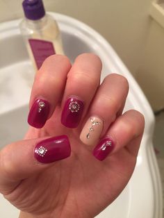 a woman's hand with red and white nail polish holding up her fingers in front of a sink