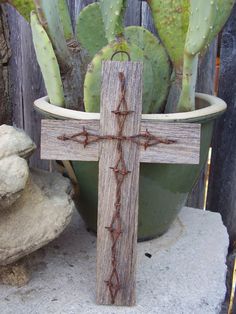 a wooden cross sitting on top of a potted plant in front of a fence