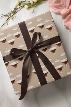 a gift wrapped in brown ribbon with martini glasses on it