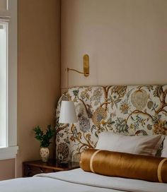 a bed sitting next to a window with white sheets and pillows on top of it