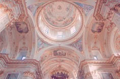 the inside of a church with ornate paintings on the walls and ceiling, along with arched doorways