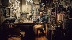 a man sitting at a desk in a room filled with antiques