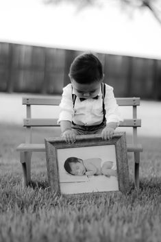 a baby is sitting on a bench with a picture frame