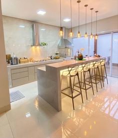 a kitchen with several stools and lights hanging from the ceiling