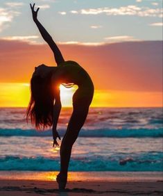 a woman doing yoga on the beach at sunset