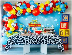 a table topped with lots of balloons next to a wall covered in animals and letters