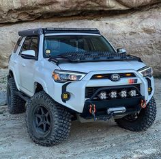 the front end of a white four - doored suv parked on top of rocks