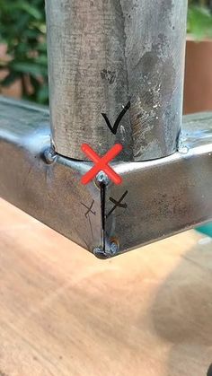 a close up of a metal object on a wooden table with plants in the background