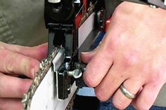 two hands are working on a piece of metal that is attached to a sewing machine