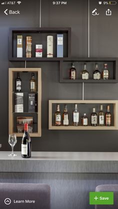 a bar with liquor bottles and wine glasses on the top shelf next to two empty shelves