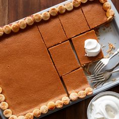 a pan with some food on top of it next to a fork and spoons