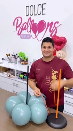 a man standing next to some balloons on a table