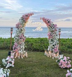 an outdoor ceremony setup with flowers and candles on the grass by the ocean at sunset