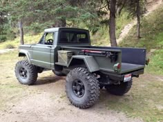 a green truck parked on top of a dirt road