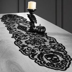 a candle is sitting on top of a table with an intricately designed runner in black and white