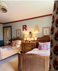 two twin beds in a bedroom with pink and white decor on the wall above them