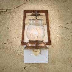 an old fashioned light fixture mounted on the side of a wall with a glass jar