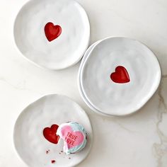 three white plates with red hearts on them