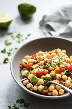 a bowl filled with chickpeas, tomatoes and avocado garnished with cilantro