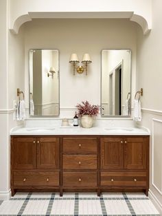 a bathroom with two sinks and mirrors on the wall next to a checkered floor