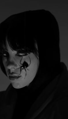 a woman with makeup on her face and black hair is looking at the camera while wearing a hoodie