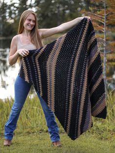 a woman holding up a black and gold striped blanket