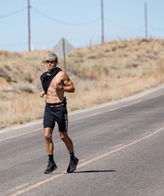 a shirtless man running down the road in shorts and sneakers with no shirt on