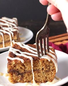 someone is holding a fork over a piece of cake on a plate with white icing