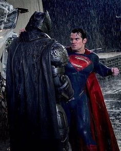 two men dressed as superman and batman in the rain