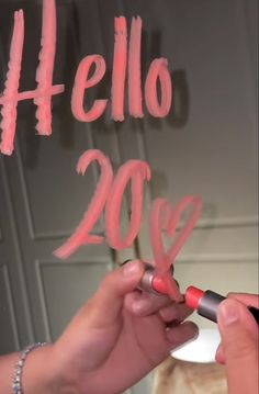 someone is writing the word hello in pink on a wall with red marker and pen