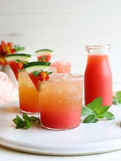 three glasses filled with watermelon, cucumber and orange juice on a white plate