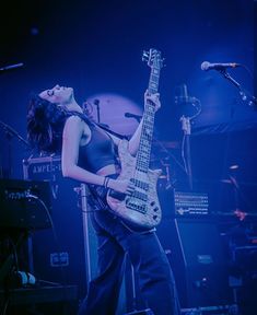 a woman standing in front of a microphone and guitar