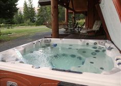 a hot tub sitting on top of a wooden deck next to a covered patio area