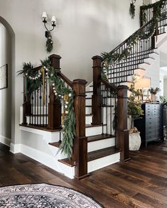 a staircase decorated for christmas with garland and greenery on the bannister railing