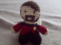 a crocheted doll with a beard and mustache sitting on top of a bed