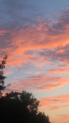 the sky is pink and blue with some clouds in it as the sun goes down