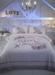 a white bed sitting under a chandelier next to a night stand with candles