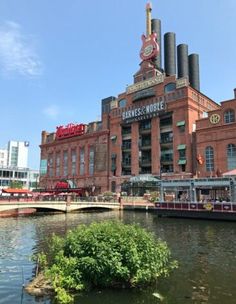 an old brick building on the side of a river with a bridge in front of it