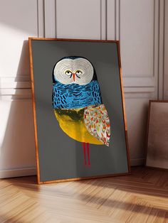 an owl sitting on top of a wooden table next to a framed photo in front of a wall