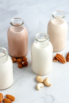 three glass jars filled with almond milk and nuts