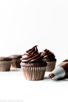 three cupcakes with chocolate frosting on them and one has a bite taken out